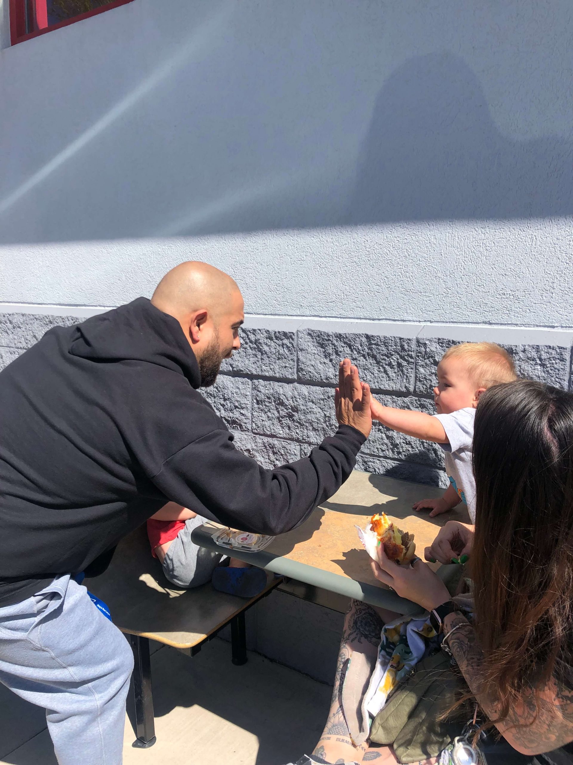 man high fiving a child in our outdoor dining space