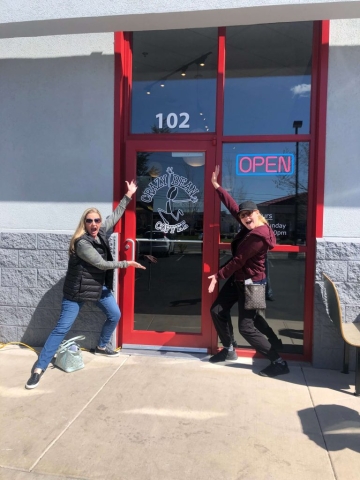 two happy customers excited to visit posing outside the cafe doors