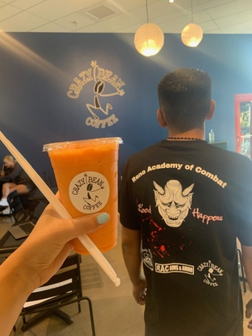 orange creamsicle iced drink held next to a reno academy of combat shirt